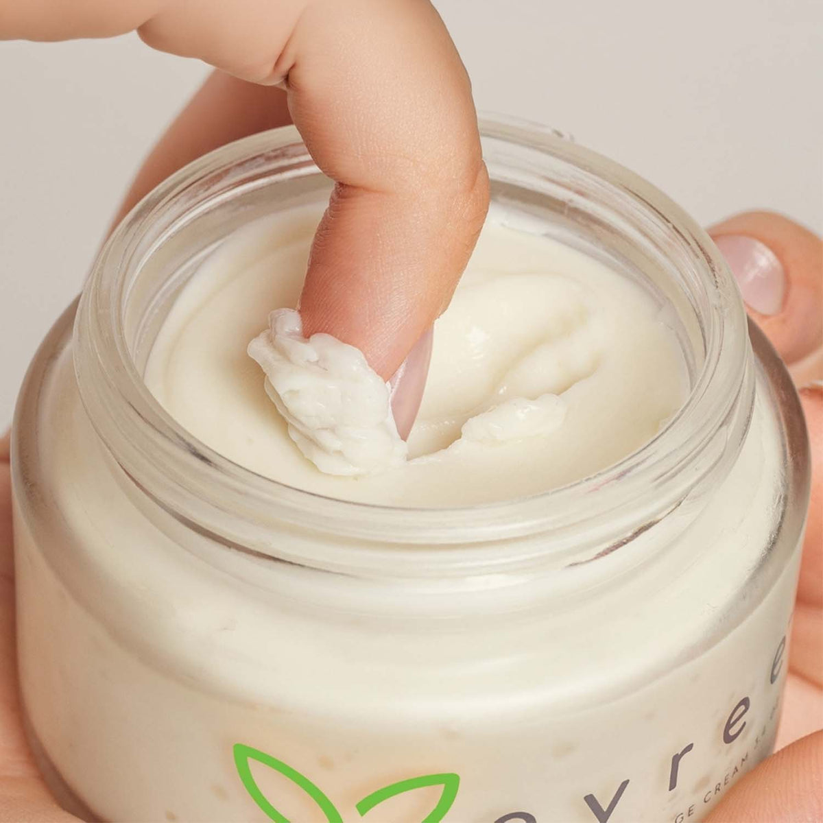 Fingertip scooping a little evree massage cream from the jar