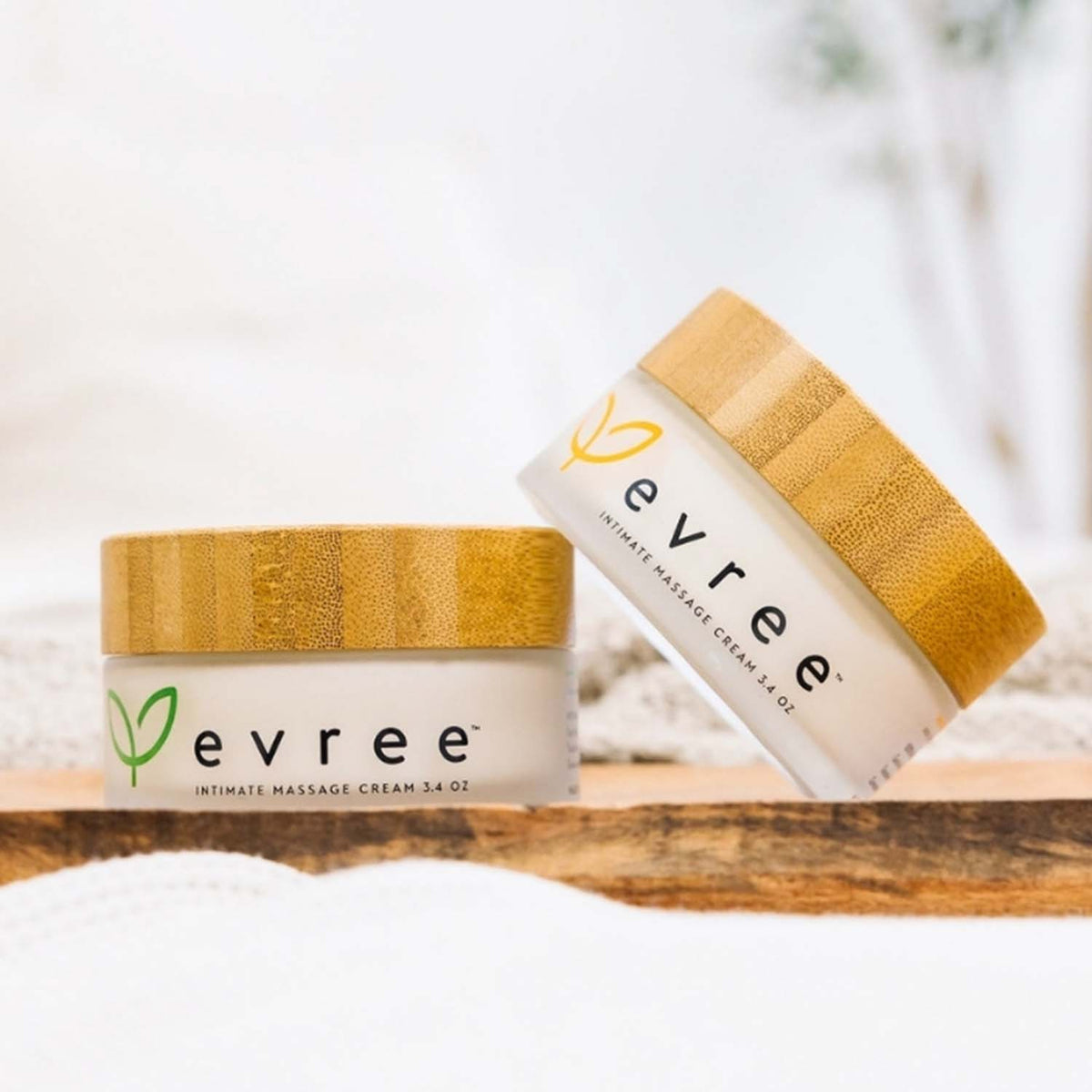 Two jars of evree intimate massage cream with bamboo lids on a wooden board